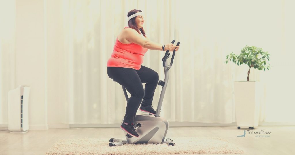 Overweight woman on an exercise bike in her front room