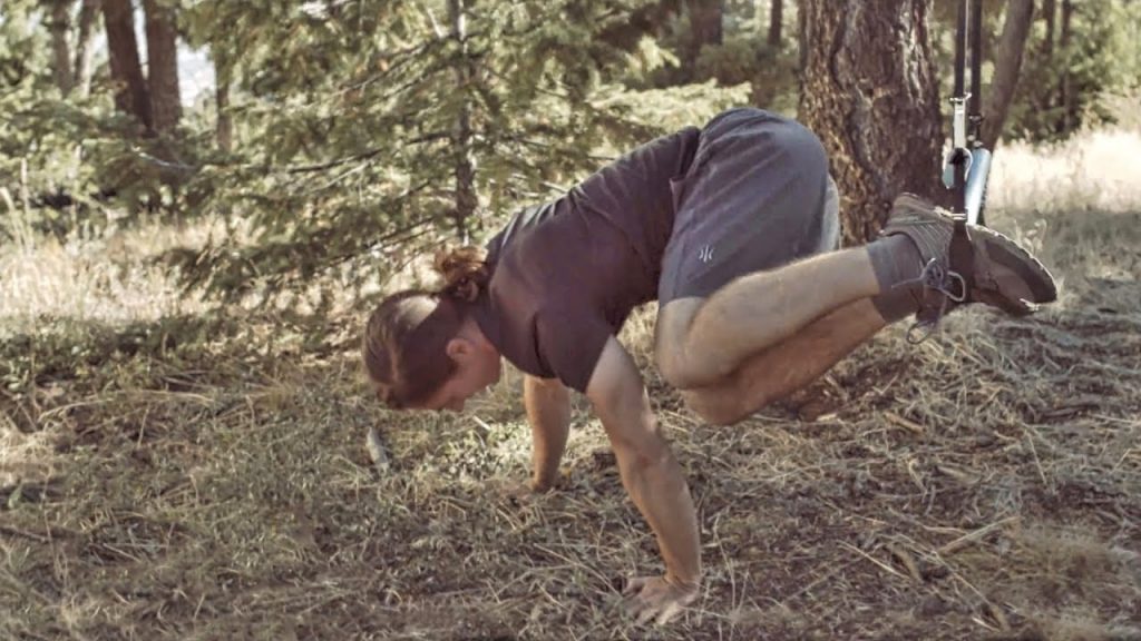 A man in the forest demonstrating a Monkii Bars review of suspension trainers