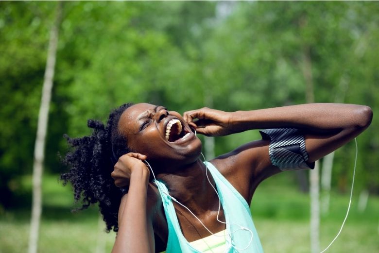 Black woman reacting to music on ipods whilst outdoor running. 