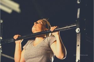 close of woman doing a pull up - dark background