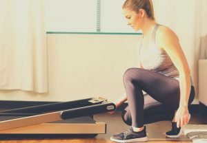 Woman pushing an under bed treadmill under