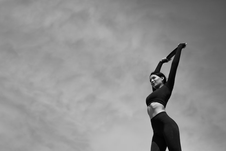 Woman outside with the grey sky as backdrop doing chest exercises with resistance bands