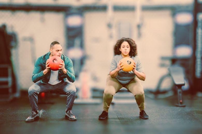 Woman & man doing squats with ball